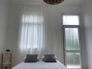a white bedroom with a bed and a window at Godson Apartment in Haifa