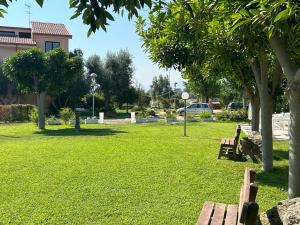 a park with two benches and trees and a car at Hotel Park in Rossano