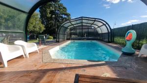 a swimming pool in a glass house with a table and chairs at Le Bois aux Cerfs in Bois-Jérôme-Saint-Ouen