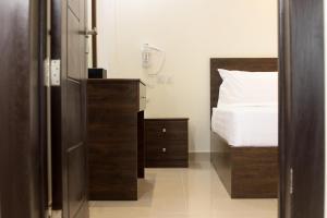 Durat Alnakheel Serviced Apartments في عنيزة: غرفة نوم بسرير وخزانة خشبية مع سرير ابيض