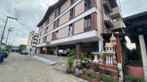 a building on the side of a street with potted plants at ธนทรัพย์อพาร์ทเม้นท์ Room02 in Pathum Thani