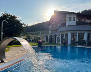 a pool with a water fountain in front of a house at Wellness & Genuss Resort - Engel Obertal in Baiersbronn
