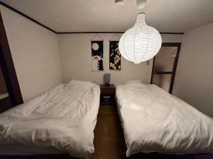 - une chambre avec 2 lits et un lustre dans l'établissement 奈良公園徒歩15分古民家リノベーション貸切一軒家 Guest House奈良紀寺, à Nara