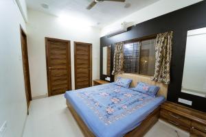 a bedroom with a bed with blue sheets and a window at The Royal Villa in Panchgani