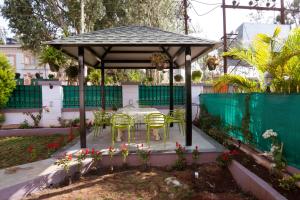 a gazebo with a table and chairs in a garden at The Royal Villa in Panchgani