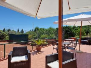 d'une terrasse avec des tables, des chaises et un parasol. dans l'établissement Villa D'Agati, à San Giorgio