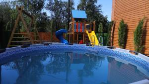 a small swimming pool with a playground next to a house at Star Villa Bakuriani in Bakuriani