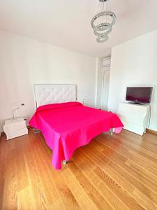 um quarto com uma cama rosa e uma televisão em La Suite sul Mare 1 em Montesilvano