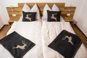 two beds with black and white pillows and deer pillows at Kitzlochklammblick Hof in Taxenbach
