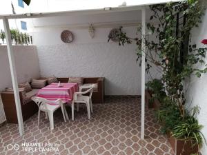 a patio with a table and chairs with a pink table cloth at Lovely house with garden in Martil