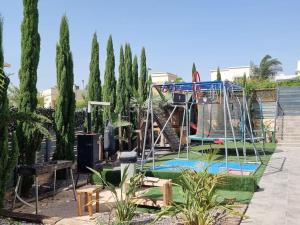 un parque infantil con un columpio en un patio con árboles en מתחם האירוח לב הגלבוע, en Nurit