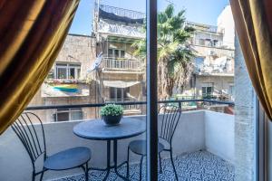 d'un balcon avec une table, des chaises et une fenêtre. dans l'établissement Sheva Urban Suites, à Jérusalem