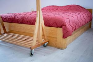 a wooden bed with a red comforter on a wooden cart at Maison Raymond - Vakantiehuisje met houtgestookte sauna 