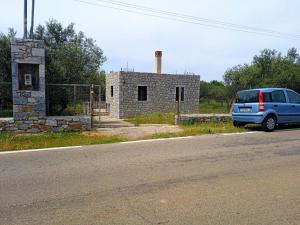 Érimos的住宿－Sotula，停在石头建筑前面的蓝色货车