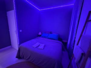 ein lila Schlafzimmer mit einem Bett mit zwei Handtüchern darauf in der Unterkunft Guest Room Bien-être et cosy près de Paris, Roissy CDG et du village Olympique in Persan
