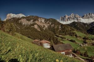 a village on a hill with mountains in the background at Putzerhof in Funes