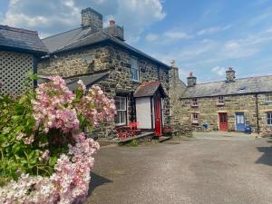 an old stone house with pink flowers in front of it at Cottage in the heart of Dolgellau in Dolgellau