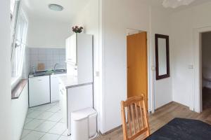 a kitchen with a white refrigerator and a wooden chair at Ferienwohnung Gartenblick in Wesenberg