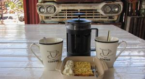 einem Tisch mit drei Kaffeetassen und einem Behälter mit Lebensmitteln in der Unterkunft Canyon Farmyard Camping in Keetmanshoop