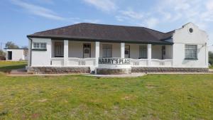 Harry's Place Guesthouse في Kamieskroon: مبنى ابيض مع لافته مكتوب عليها سهول المحرق