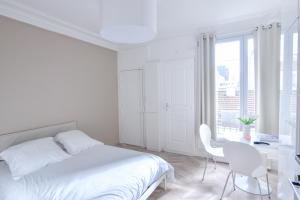 a white bedroom with a bed and a desk and a window at Studio 1 Pièce 20 m2 in Paris