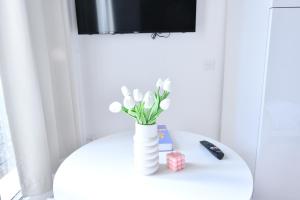 a white vase with white flowers on a table at Studio 1 Pièce 20 m2 in Paris