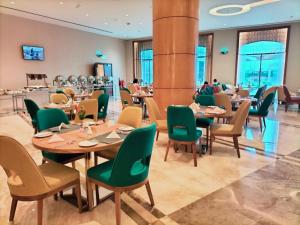 塞拉莱Tulip Inn Majan Hotel and Suites Salalah的有木桌和绿色椅子的餐厅