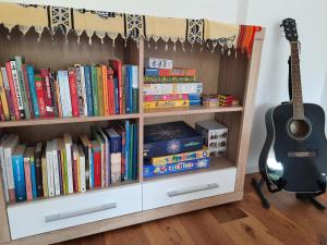 a book shelf filled with books and a guitar at Happy Place in Ig