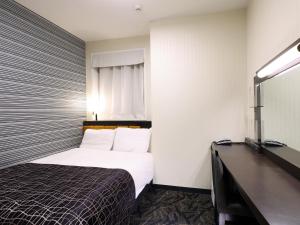 una habitación de hotel con una cama y un escritorio en APA Hotel Shizuoka-eki Kita, en Shizuoka
