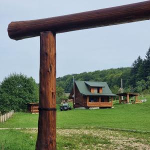 a log cabin in a field with a wooden pole at Vysoka brama дерев'яний будиночок з чаном in Oriv