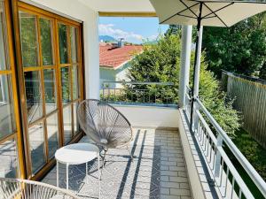 a balcony with a chair and an umbrella at LIKE HOME, cozy apartment, 2 bedrooms, Netflix, 55" TV, balcony, parking, self-check-in in Penzberg