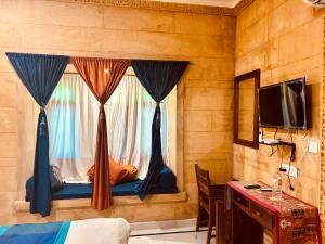 Schlafzimmer mit einem Bett und einem Fenster mit Vorhängen in der Unterkunft Hotel Heritage Haveli in Jaisalmer