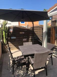 un tavolo e sedie con un ombrellone in un patio di Pavillon 3 chambres avec véranda et climatisation. a Sorède