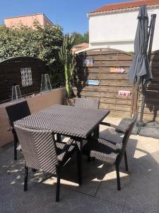 un tavolo, sedie e un ombrellone in un patio di Pavillon 3 chambres avec véranda et climatisation. a Sorède