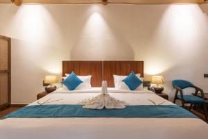 Un dormitorio con una cama grande con almohadas azules. en Shanthi Kunnj Riverside Exotica Chikmagalur, en Chikmagalur