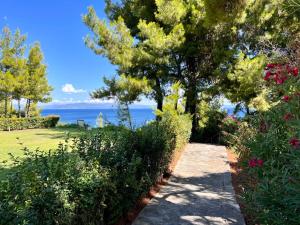 a path through a garden with the ocean in the background at Cute house by the sea in Kriopigi