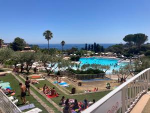 a group of people sitting in the grass by a pool at L'écrin du Cap Esterel in Saint-Raphaël