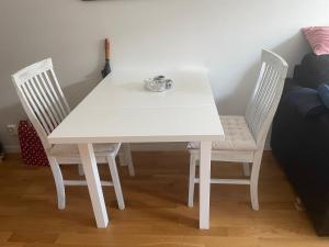 a white table with two chairs and a cup on it at Fin lägenhet med balkong - Centralt o bra läge in Käringön +4 photos