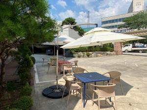 a patio with tables and chairs and an umbrella at Buan Tree California Hotel in Buan