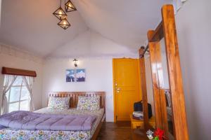 a bedroom with a bed and a yellow door at Moksham Himalayan Campsite Pangot in Nainital