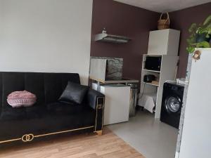 ein Wohnzimmer mit einem schwarzen Sofa und einer Küche in der Unterkunft DANA S HOME in La Courneuve