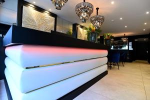 a lobby with a white reception desk with chandeliers at Hôtel Des Quatrans in Caen