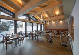 a dining room with tables and chairs and windows at Mirabeau Etoile in Zermatt