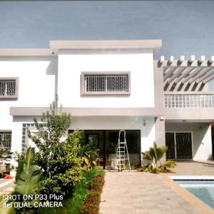 a white house with a ladder in front of it at Villa magnifique avec piscine in Somone