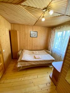um quarto com uma cama num quarto de madeira em Zyma_Lito Guest House em Yaremche