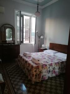 a bedroom with a bed with a flowered blanket on it at Battisti 18 Vintage Rooms in Palermo