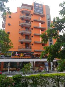 um edifício laranja com um restaurante em frente em Astúrias Praia Hotel no Guarujá