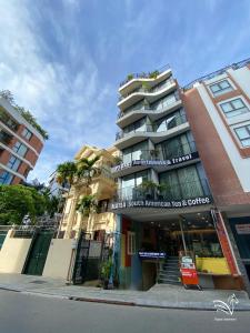 a tall building on a city street with palm trees at Pegasy Apartments & Travel in Hanoi