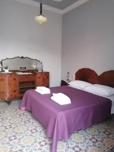 a bedroom with a purple bed and a table with towels at Battisti 18 Vintage Rooms in Palermo