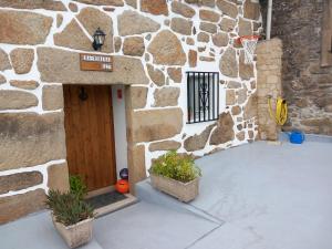 un edificio de piedra con un aro de baloncesto delante de una puerta en Casa da Eiriña, en Amés
